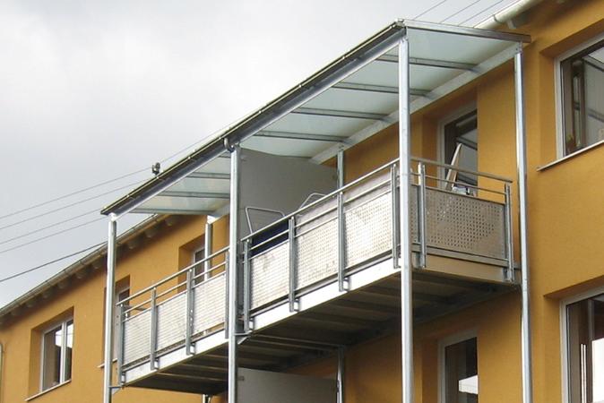 Stahlbalkon verzinkt mit Geländer, Füllung Lochblech verzinkt, Überdachung aus Glas VSG 10mm mit                             mattweißer Folie