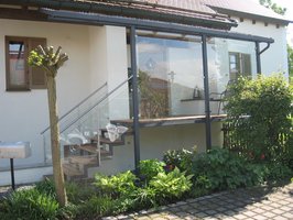 Hauseingansgüberdachung mit Stahltreppe verzinkt lackiert, Geländer aus Edelstahl und Glas, Belag                   aus Tropenholz