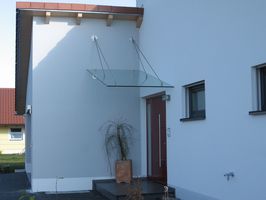 Eingangsüberdachung schräg abgehängt aus Edelstahl mit Verglasung